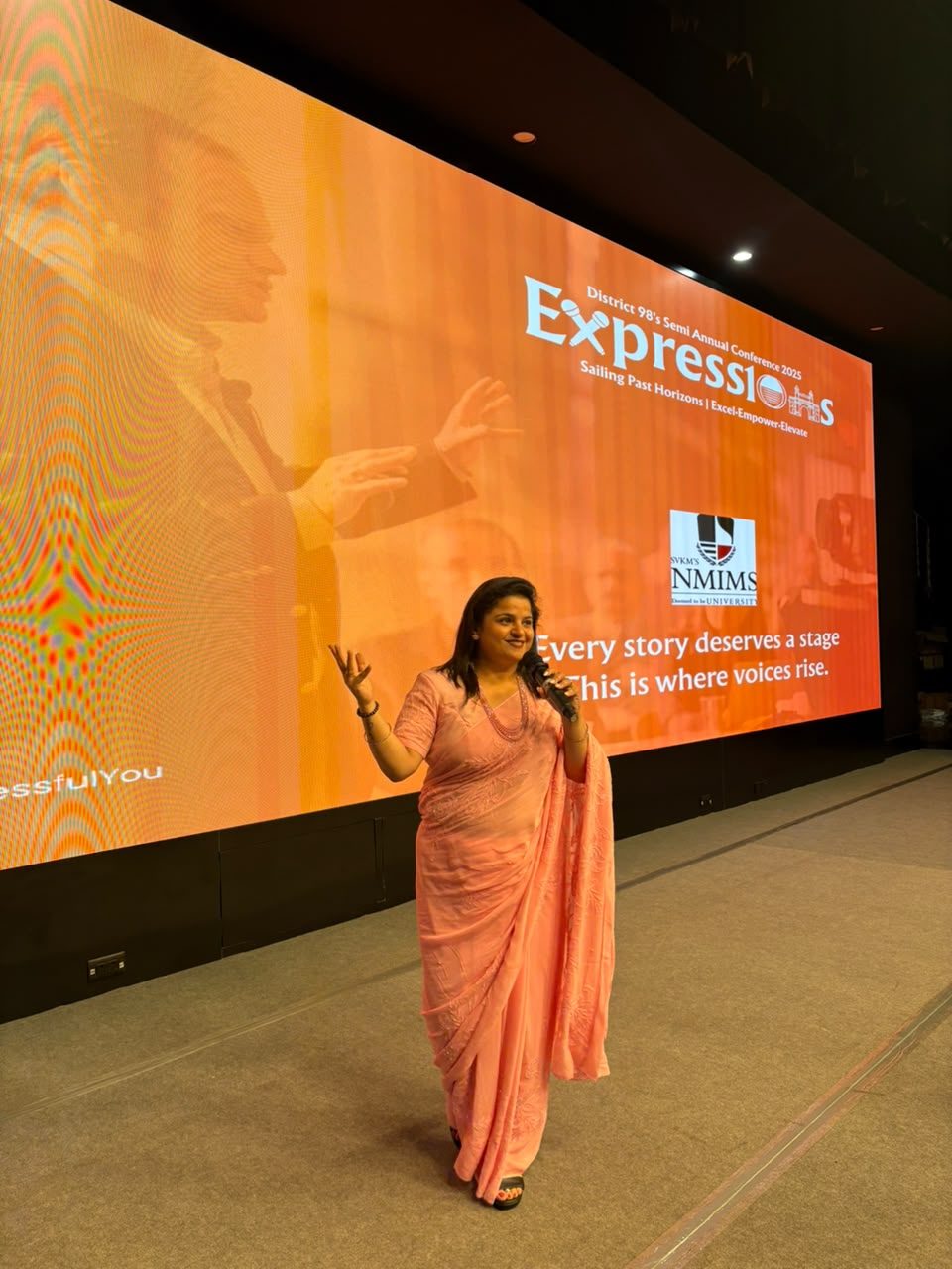 Shipra delivering a keynote in a pink sari
